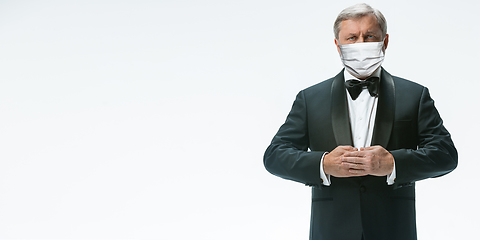 Image showing Elegance senior man waiter in protective face mask on white background. Flyer with copyspace.