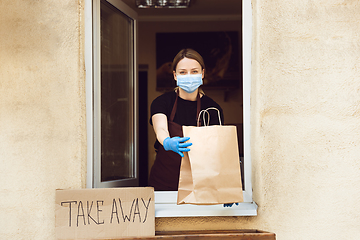 Image showing Woman preparing drinks and meals, wearing protective face mask and gloves. Contactless delivery service during quarantine coronavirus pandemic. Take away only concept.