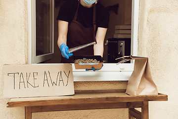 Image showing Woman preparing drinks and meals, wearing protective face mask and gloves. Contactless delivery service during quarantine coronavirus pandemic. Take away only concept.