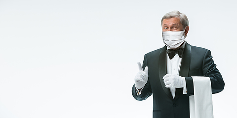 Image showing Elegance senior man waiter in protective face mask on white background. Flyer with copyspace.