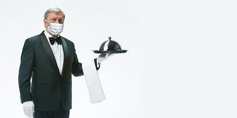 Image showing Elegance senior man waiter in protective face mask on white background. Flyer with copyspace.