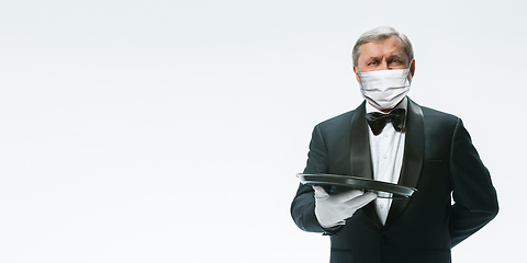 Image showing Elegance senior man waiter in protective face mask on white background. Flyer with copyspace.