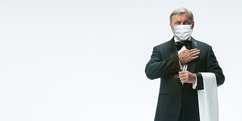 Image showing Elegance senior man waiter in protective face mask on white background. Flyer with copyspace.