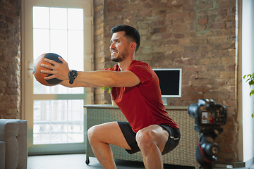 Image showing Young caucasian man training at home during quarantine of coronavirus outbreak, doing exercises of fitness, aerobic. Staying sportive during insulation.