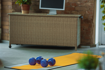 Image showing Blue dumbbells lying on yellow yoga mat. Fitness, aerobic. Staying sportive during insulation.