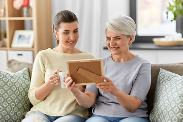 Image showing adult daughter and old mother with photo at home