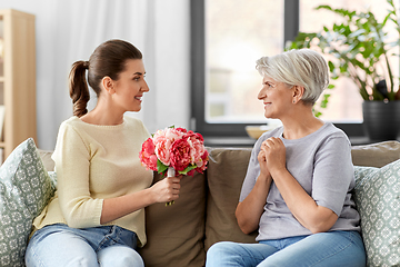 Image showing adult daughter giving flowers to old mother