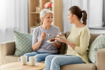 Image showing old mother and adult daughter eating cake at home