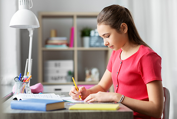 Image showing student girl with ruler drawing line in notebook