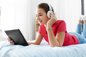 Image showing girl in headphones listening to music on tablet pc