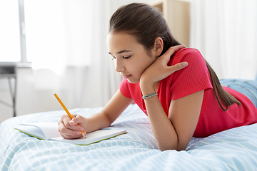 Image showing teenage girl writing to diary at home