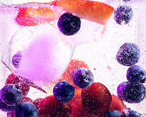 Image showing Close up view of the cold and fresh lemonade with bright berries in neon light