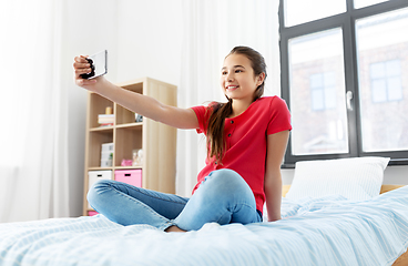 Image showing happy girl with smartphone taking selfie at home