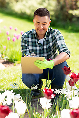 Image showing man with clipboard and flowers at summer garden