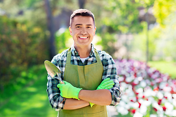 Image showing happy man in apron with scoop at summer garden