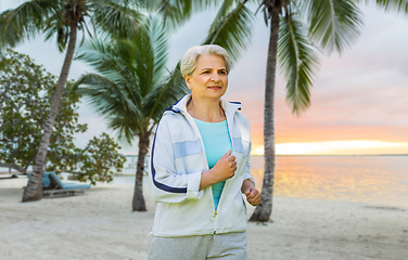 Image showing senior woman running along summer park