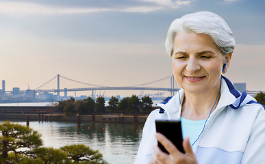 Image showing sporty senior woman with earphones and smartphone