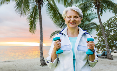 Image showing senior woman with dumbbells exercising at park