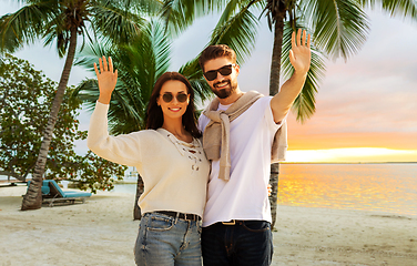 Image showing happy couple waving hands on beach