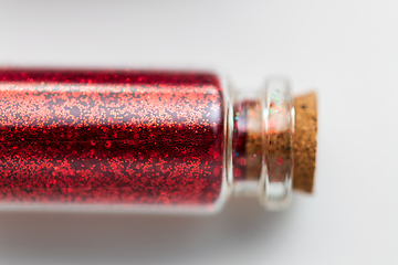 Image showing red glitters in bottle over white background