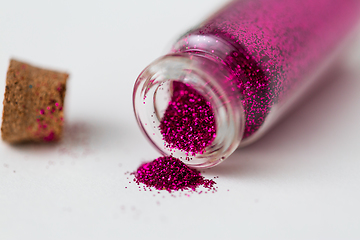 Image showing pink glitters poured from small glass bottle