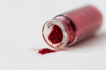 Image showing red glitters poured from small glass bottle