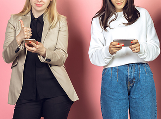 Image showing Two girls, friends using mobile smartphones. Teenagers addiction to new technology trends. Close up.