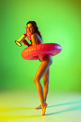 Image showing Beautiful girl in fashionable swimsuit isolated on gradient studio background in neon light. Summer, resort, fashion and weekend concept