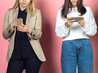 Image showing Two girls, friends using mobile smartphones. Teenagers addiction to new technology trends. Close up.