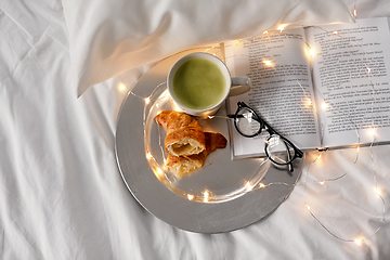 Image showing croissants, matcha tea, book and glasses in bed