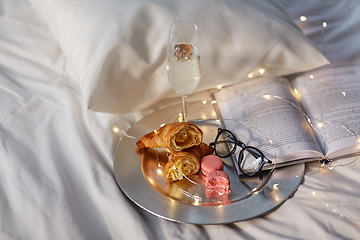 Image showing champagne, croissants, book and glasses in bed