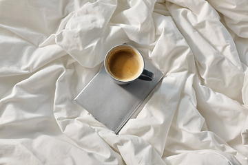 Image showing cup of coffee with book in bed