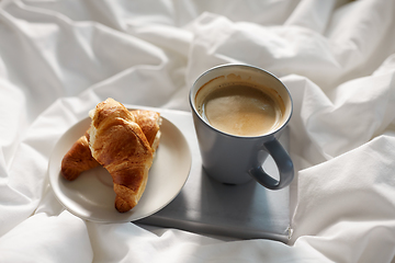 Image showing croissants, cup of coffee and book in bed at home