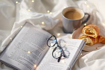 Image showing croissants, cup of coffee, book and glasses in bed