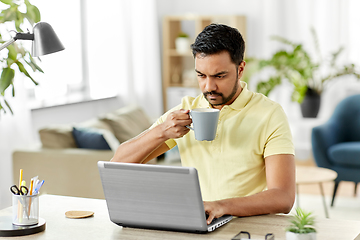 Image showing man with laptop drinking coffee at home office