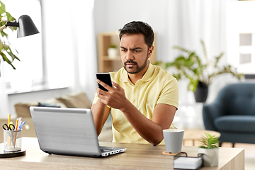 Image showing happy indian man with smartphone at home office