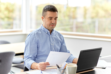 Image showing man in earphones with laptop working at home