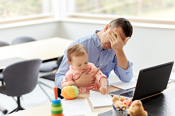 Image showing father with baby working on laptop at home office