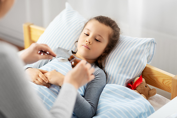 Image showing mother pouring cough syrup for sick daughter