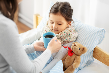 Image showing mother giving hot tea to sick little daughter