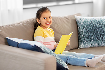 Image showing happy smiling little girl reading book at home