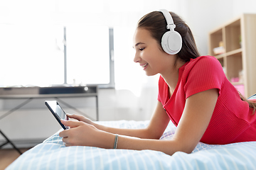 Image showing girl in headphones listening to music on tablet pc