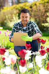 Image showing man with clipboard and flowers at summer garden