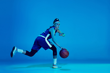 Image showing Young caucasian female basketball player isolated on blue studio background in neon light