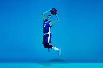 Image showing Young caucasian female basketball player isolated on blue studio background in neon light