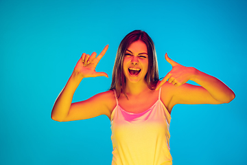 Image showing Caucasian young woman\'s portrait isolated on blue background in neon light