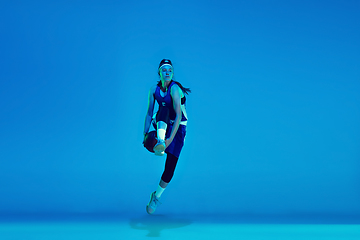 Image showing Young caucasian female basketball player isolated on blue studio background in neon light