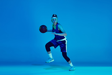 Image showing Young caucasian female basketball player isolated on blue studio background in neon light