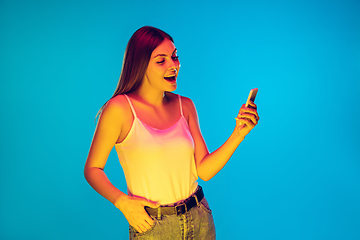 Image showing Caucasian young woman\'s portrait isolated on blue background in neon light