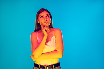 Image showing Caucasian young woman\'s portrait isolated on blue background in neon light